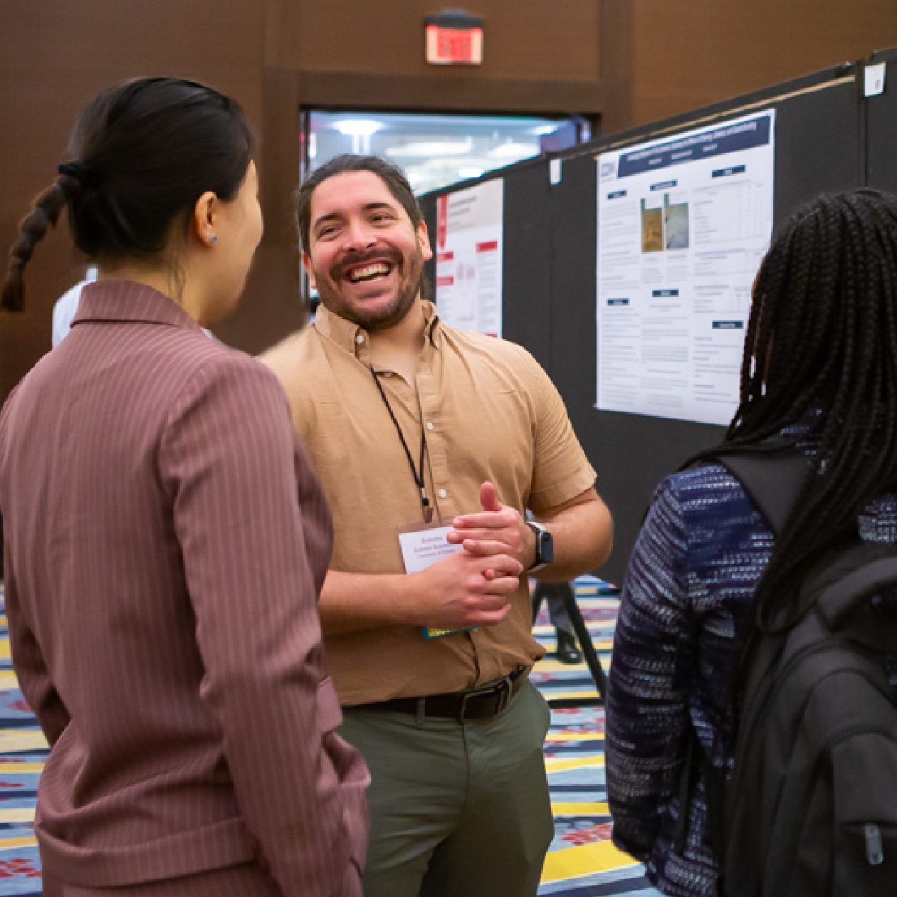 Graduate students stand discussing research in front of posters at a conference
